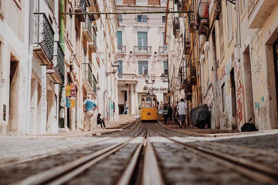 A narrow tiled street in Alfama with a passing tram