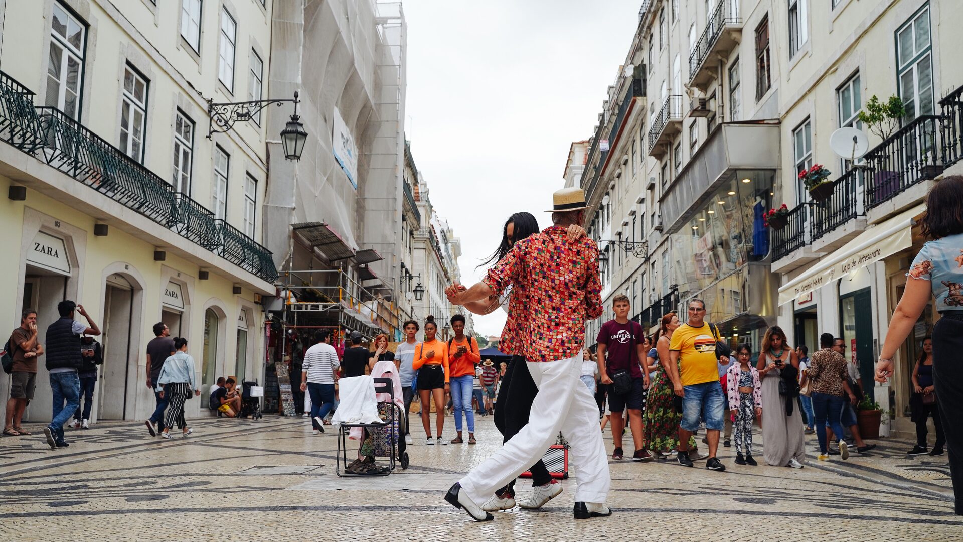 A couple dancing for onlookers on the mosaic pavement of Rua Augusta