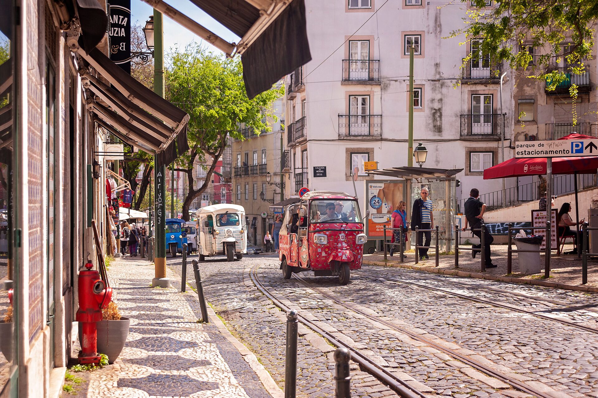 Tuk-tuks waiting on a cobbled tram street below the Santa Luzia viewpoint in Alfama