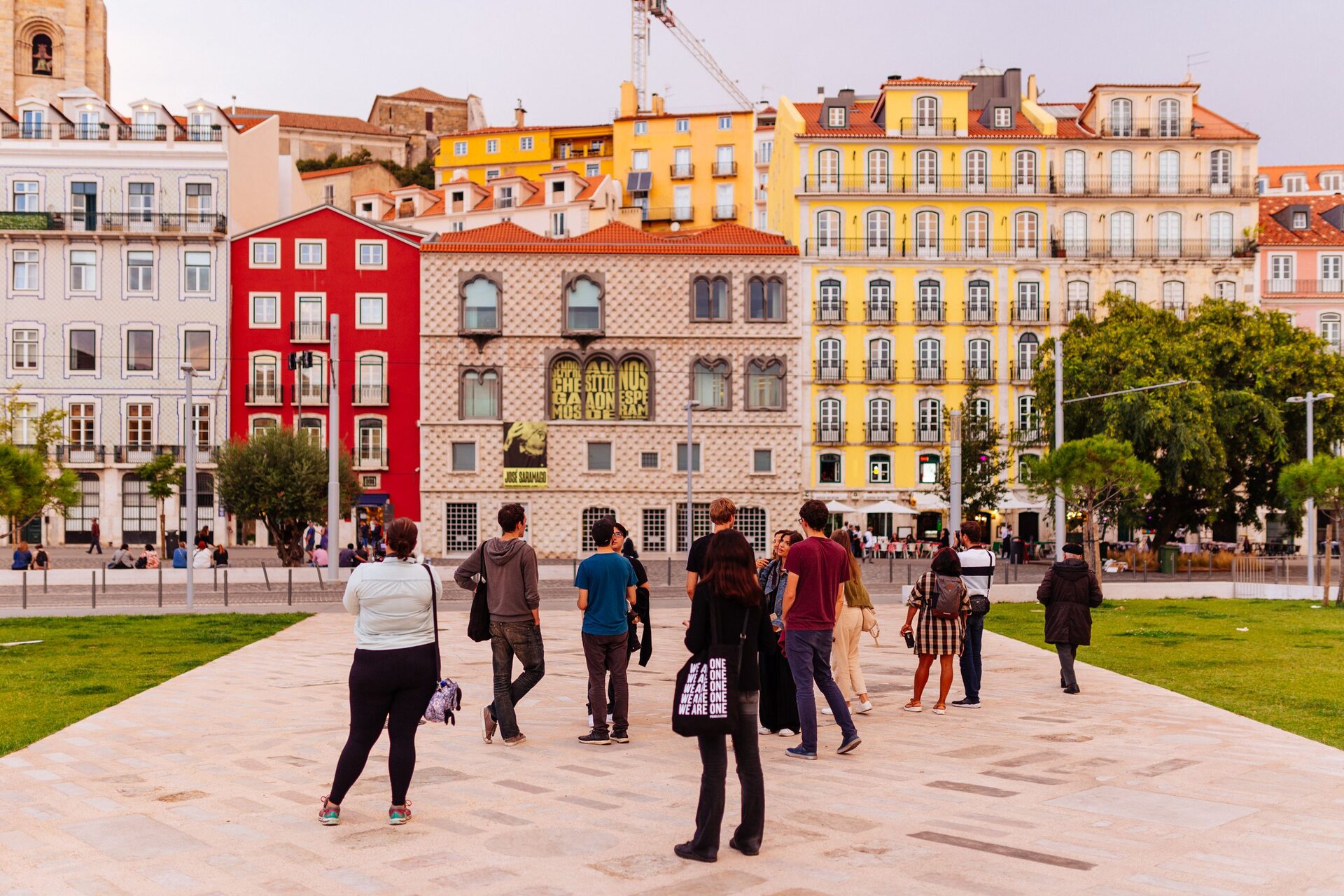 A walking group in front of the painted facades and Casa dos Bicos at Campo das Cebolas