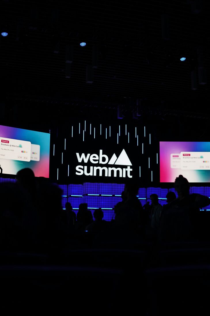 Attendees at a Web Summit meetup, silhouetted against screens under the Web Summit logo